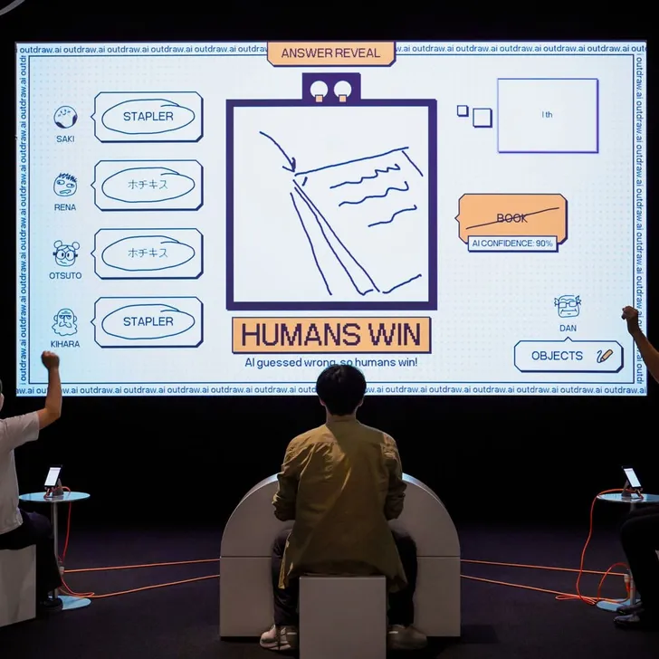 Players cheering in front of a drawing game on a large screen